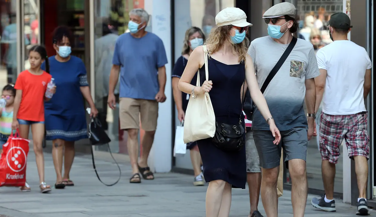 <p>Orang-orang memakai masker saat berjalan di Brussel, Belgia, Rabu (12/8/2020). Penggunaan masker menjadi wajib di tempat umum di Brussel karena kasus Covid-19 naik ke tingkat kewaspadaan yang menempatkan kota itu di antara yang paling parah terkena dampak corona di Eropa. (Fran&ccedil;ois WALSCHAERTS/AFP)</p>