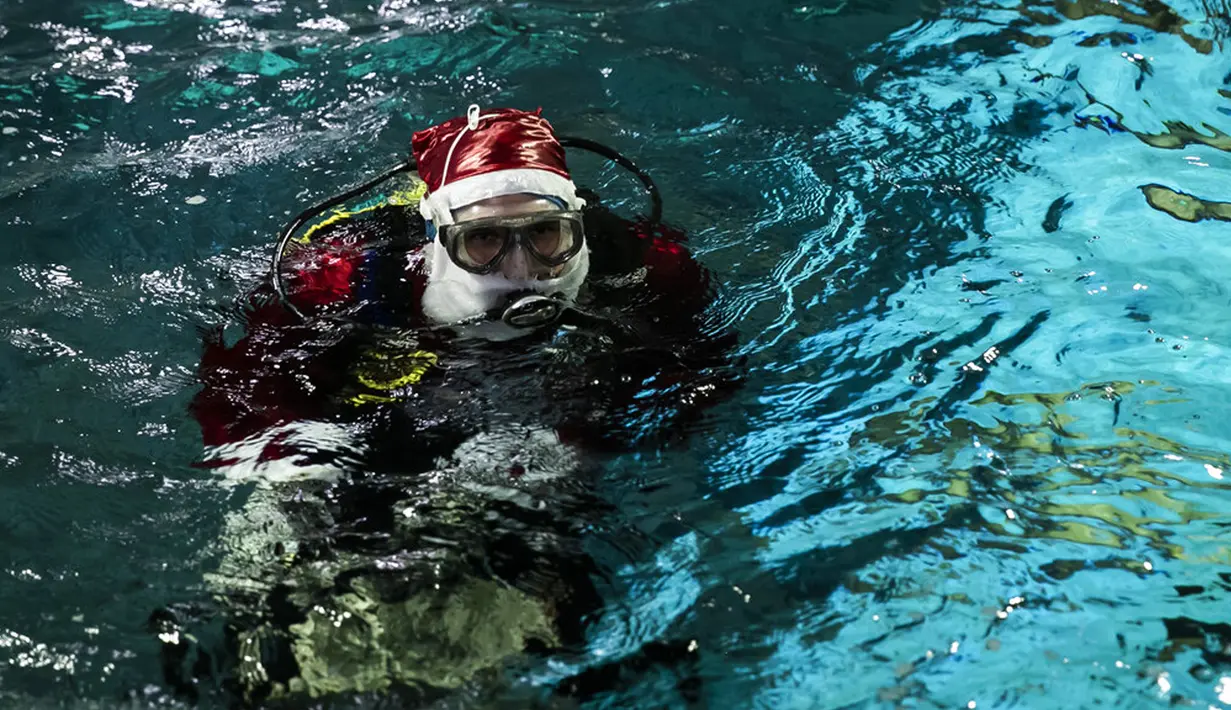 Aquarist Volmer Salvador bersiap berenang dalam akuarium AquaRio mengenakan kostum Sinterklas saat musim Natal di Rio de Janeiro, Brasil, 20 Desember 2021. Dengan luas bangunan sekitar 26.000 meter persegi, AquaRio dianggap sebagai akuarium laut terbesar di Amerika Selatan. (AP Photo/Bruna Prado)