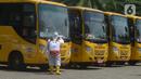 Petugas ber-APD menyemprotkan disinfektan pada bus sekolah di Posko Gabungan PSBB dan Gakplin Protkes, Puskesmas Jatinegara, Jakarta, (22/9/2020). Sejumlah unit bus sekolah kini dialihfungsikan menjadi kendaraan untuk mengantar pasien Covid-19 berstatus OTG menuju Wisma Atlet. (merdeka.com/Imam Buho
