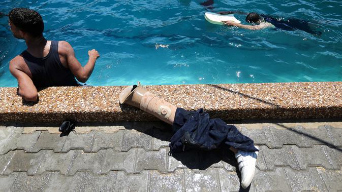 Kaki palsu terlihat di dekat kolam renang ketika warga Palestina berlatih di bawah instruksi Majdi al-Tatar di Gaza (30/7/2019). Tatar, yang kehilangan kaki kanannya akibat kecelakaan pada masa kecilnya, melatih warga Palestina yang diamputasi selama konflik dengan Israel. (AFP Photo/Mahmud Hams)