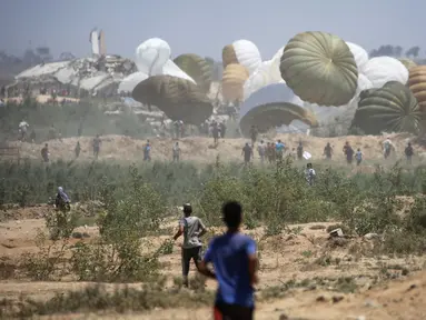 Warga Palestina bergegas menuju lokasi pendaratan paket bantuan yang diterjunkan di wilayah Nuseirat, Jalur Gaza tengah, saat penerjunan bantuan dari udara di atas wilayah Palestina yang dikepung Israel pada 6 Agustus 2025. (Eyad BABA/AFP)