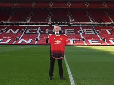 Ole Gunnar Solskjaer menunjukkan jersey Manchester United saat konferensi pers di Stadion Old Trafford, Inggris, (28/3). Manchester United resmi mengumumkan Solskjaer sebagai pelatih permanen mereka untuk beberapa tahun ke depan. (AFP Photo/Oli Scarff)