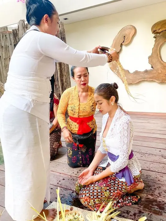 Jessica Iskandar tampil berbalut kebaya putih, kain batik dan sabuk ungu saat menjalani ritual melukat. @inijedar.