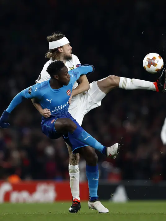 Pemain Ostersunds FK, Tom Pettersson berebut bola dengan striker Arsenal, Danny Welbeck pada laga leg kedua 32 Liga Europa 2017-2018 di Stadion Emirates, Kamis (22/2). Arsenal melaju ke babak 16 besar Liga Europa meski kalah 1-2. (Adrian DENNIS/AFP)