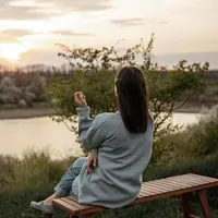 Seorang perempuan sedang menikmati senja di tepi sebuah danau (Foto Dok: Freepik/pvproductions).