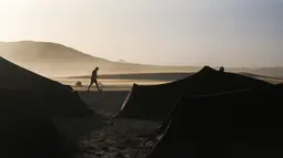 Seorang peserta berjalan di antara tenda sebelum memulai kembali mengikuti kompetisi Marathon des Sables ke-33 di gurun Sahara, Maroko (13/4). (AP Photo / Mosa'ab Elshamy)