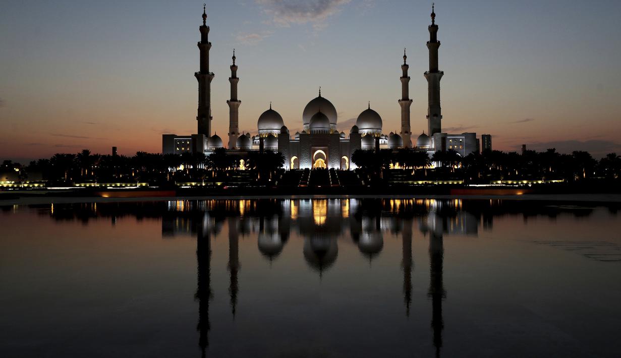 Matahari terbenam di belakang Masjid Agung Sheikh Zayed di Abu Dhabi, Uni Emirat Arab (8/11/2019). Masjid Agung Sheikh Zayed di bangun pada tahun 1996 dengan 82 kubah bergaya Maroko dan semuanya dihias dengan batu pualam putih. (AFP Photo/Kamran Jebreili)