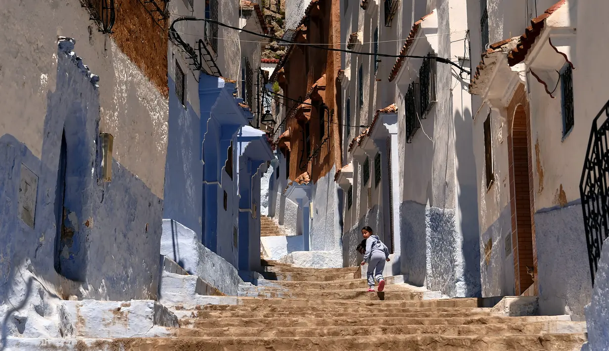 Seorang anak berjalan disebuah anak tangga di Kota Chefchaouen, Maroko, Minggu (1/5). Chefchaouen baru-baru ini dinobatkan sebagai kota terindah keenam dari 50 kota di dunia menurut Conde Nast Traveler. (FADEL SENNA / AFP)