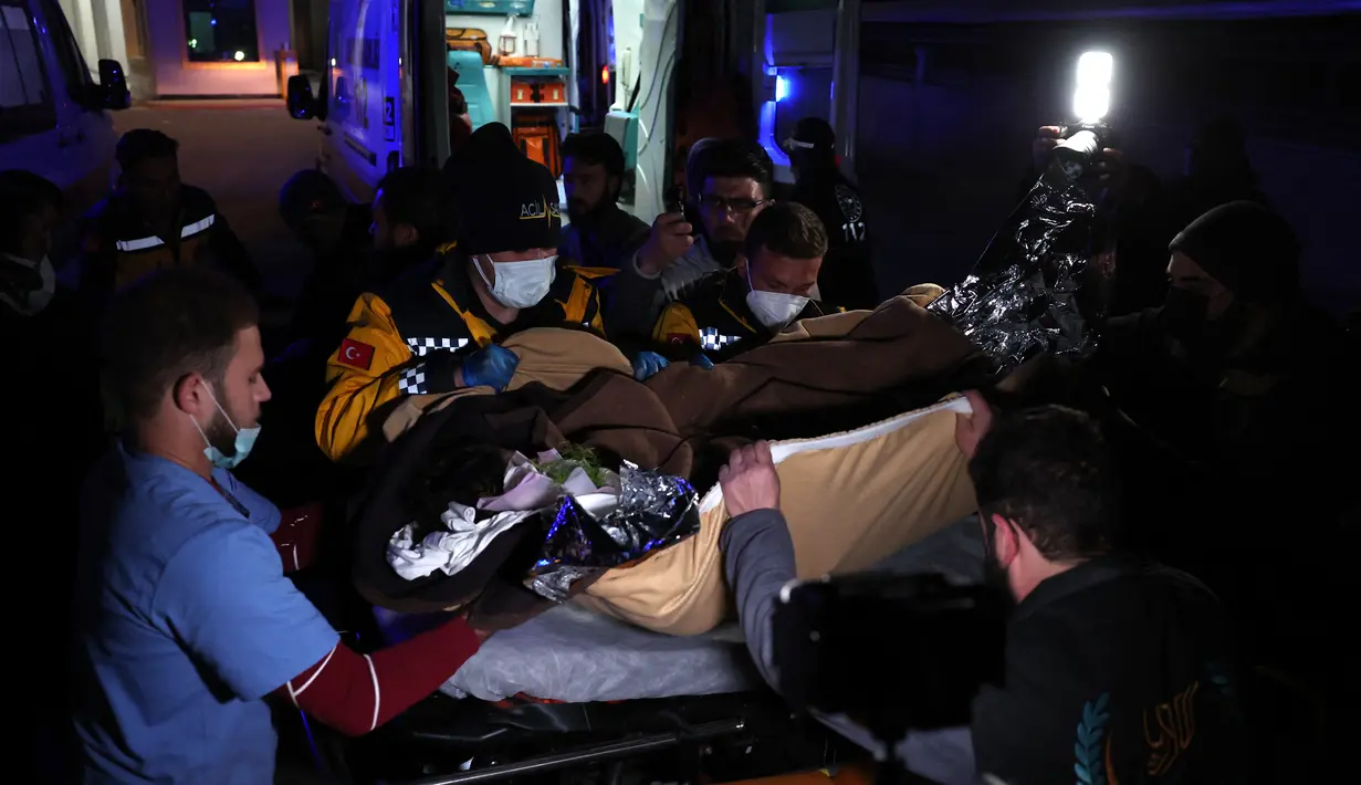Petugas medis mengangkut Sham Sheikh Mohammed ke ambulans di perbatasan Bab al-Hawa pada 23 Februari 2023, sebelum memasuki Turki untuk perawatan. Sham, seorang gadis Suriah berusia sembilan tahun yang nasibnya menangkap tragedi, harapan dan patah hati gempa bulan ini setelah menghabiskan 40 jam di bawah reruntuhan dibawa ke Turki untuk dirawat. (AFP/OMAR HAJ KADOUR)