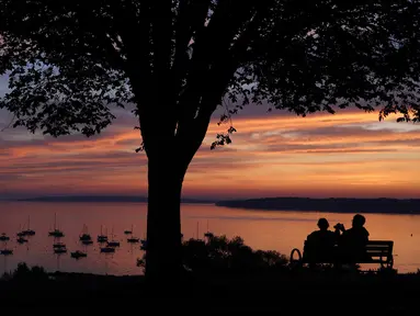 Pasangan menikmati teluk Casco saat matahari di Portland, Maine (21/8/2019). Casco Bay adalah saluran masuk Teluk Maine di pantai selatan Maine, New England, Amerika Serikat. (AP Photo/Robert F. Bukaty)