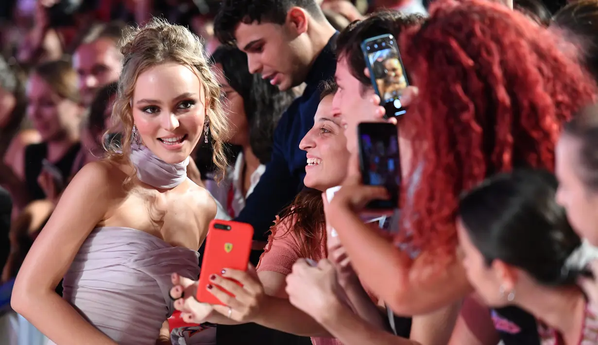 Aktris Lily-Rose Depp berselfie dengan penggemarnya saat tiba menghadiri pemutaran perdana film 'The King' di Festival Film Venice edisi ke-76, Venice, Italia (2/9/2019). Lily-Rose tampil memesona berbalut gaun berwarna pink di karpet merah Venice Film Festival 2019. (AFP Photo/Alberto Pizzoli)