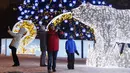 Orang-orang berswafoto dengan latar belakang instalasi lampu untuk menyambut libur Tahun Baru dan Natal Ortodoks di Moskow, Rusia, pada 29 Desember 2020. (Xinhua/Alexander Zemlianichenko Jr)