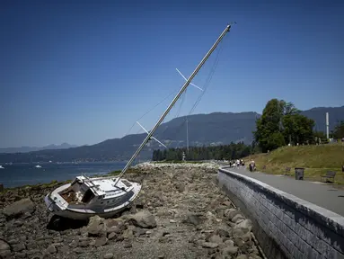Seorang pelari berlari melewati perahu yang terdampar di Vancouver, British Columbia, Minggu, 7 Juli 2024. (Ethan Cairns/The Canadian Press via AP)