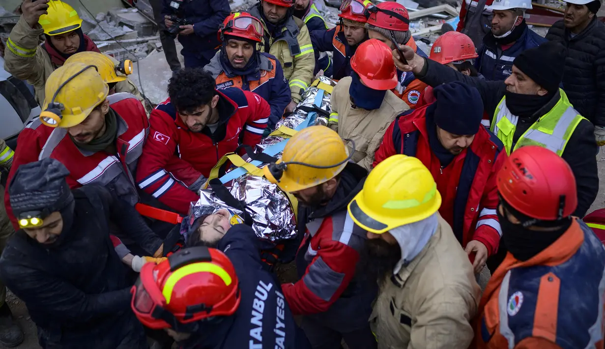 Tim penyelamat mengevakuasi seorang gadis Suriah berusia 12 tahun, Cudi, dari puing-puing bangunan yang hancur di Hatay, Turki, setelah gempa berkekuatan 7,8 melanda tenggara negara itu, Minggu (12/2/2023). Hatay, yang berbatasan dengan barat laut Suriah adalah provinsi terparah di Turki yang terkena gempa dahsyat.  (Photo by Yasin AKGUL / AFP)