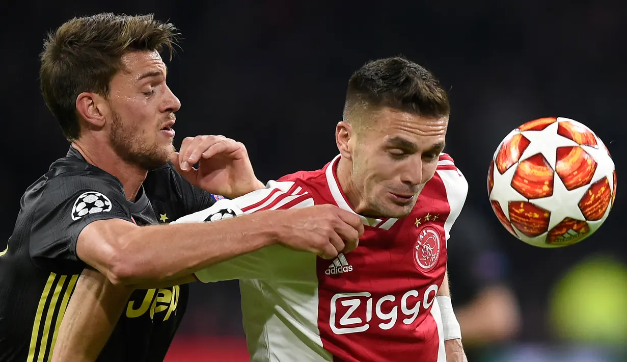 Bek Juventus, Daniele Rugani berebut bola dengan penyerang Ajax Amsterdam, Dusan Tadic pada laga pertama perempat final Liga Champions 2018-2019 di Amsterdam Arena, Rabu (10/4). Juventus harus puas bermain imbang 1-1 di kandang Ajax Amsterdam. (EMMANUEL DUNAND / AFP)