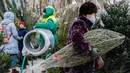 Seorang wanita membawa pohon untuk perayaan Tahun Baru di sebuah pasar di pusat kota Moskow, Rusia (27/12/2020). Pohon Tahun Baru pertama kali dibawa ke Rusia oleh Peter the Great. (Xinhua/Maxim Chernavsky)