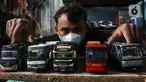 Perajin memamerkan miniatur bus di Workshop Belang Bentong, Limo, Depok, Jawa Barat, Jumat (14/1/2022). Kerajinan miniatur bus berbahan baku akrilik dan resin tersebut dipasarkan ke berbagai daerah dengan harga Rp 700 ribu hingga Rp 1 juta per unit. (Liputan6.com/Johan Tallo)