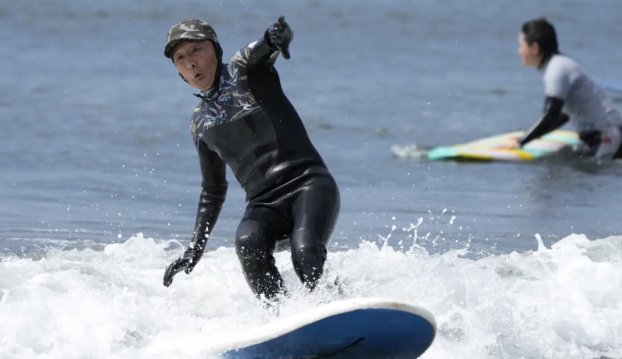Seiichi Sano, pria Jepang berusia 89 tahun, meniti ombak saat bermain "surfing" (selancar) di Pantai Katase Nishihama, di Fujisawa, selatan Tokyo, Kamis (30/3/2023). (AP Photo/Eugene Hoshiko)