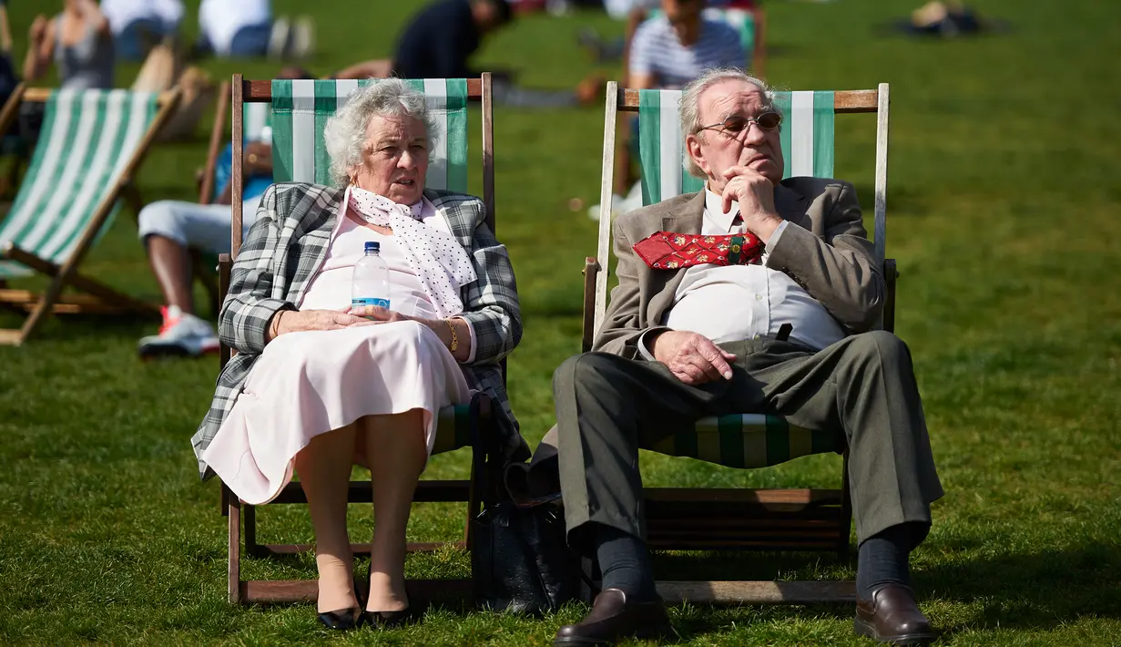 Sepasang lansia bersantai menikmati sinar matahari di atas kursi di Green Park, pusat kota London, Rabu (4/5). Awal Mei, suhu udara hangat mulai menyelimuti kota London. (Niklas HALLE'N/AFP)