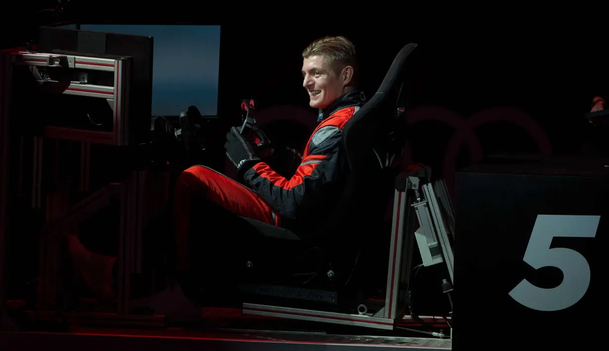 Gelandang Real Madrid, Toni Kroos tersenyum setelah menyelesaikan balapan di simulator Formula E selama sebuah acara promosi di Madrid, Spanyol, (23/11). (AP Photo / Paul White)