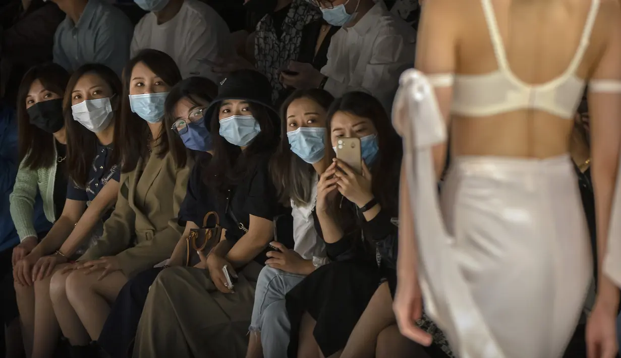 Para peserta mengenakan masker wajah untuk melindungi diri dari COVID-19 saat menonton model menampilkan kreasi perancang busana dari Finelycup dalam China Fashion Week di Beijing, China, Selasa (7/9/2021). (AP Photo/Mark Schiefelbein)
