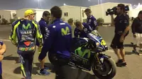 Pebalap Movistar Yamaha, Valentino Rossi (bertopi kuning), memandangi motor YZR-M1 miliknya setelah crash pada hari kedua tes MotoGP 2017 di Sirkuit Losail, Qatar, Sabtu (11/3/2017). (Bola.com/Twitter/izaskunruiz)