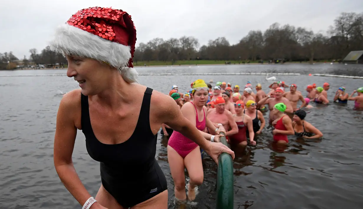 Sejumlah perenang naik meninggalkan danau usai mengikuti lomba berenang di Danau Serpentine di Hyde Park, London, Inggris, Minggu (25/12). Lomba ini digelar untuk merayakan Natal 2016. (REUTERS/Toby Melville)
