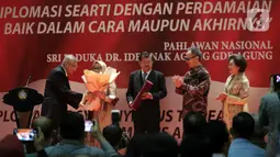 Wakil Presiden ke-10 dan ke-12 RI Jusuf Kalla (tengah) saat menerima anugerah dari Pembina Yayasan Sekar Manggis Anak Agung Gde Agung (kiri) saat penyerahan penghargaan Anugerah Dr Ide Anak Agung Gde Agung di Kantor Kementerian Luar Negeri, Jakarta, Kamis (23/1/2020). (Liputan6.com/Faizal Fanani)