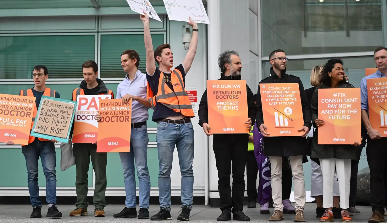 Dalam aksinya, beberapa pekerja membawa poster berisi tuntutan mereka. (JUSTIN TALLIS/AFP)