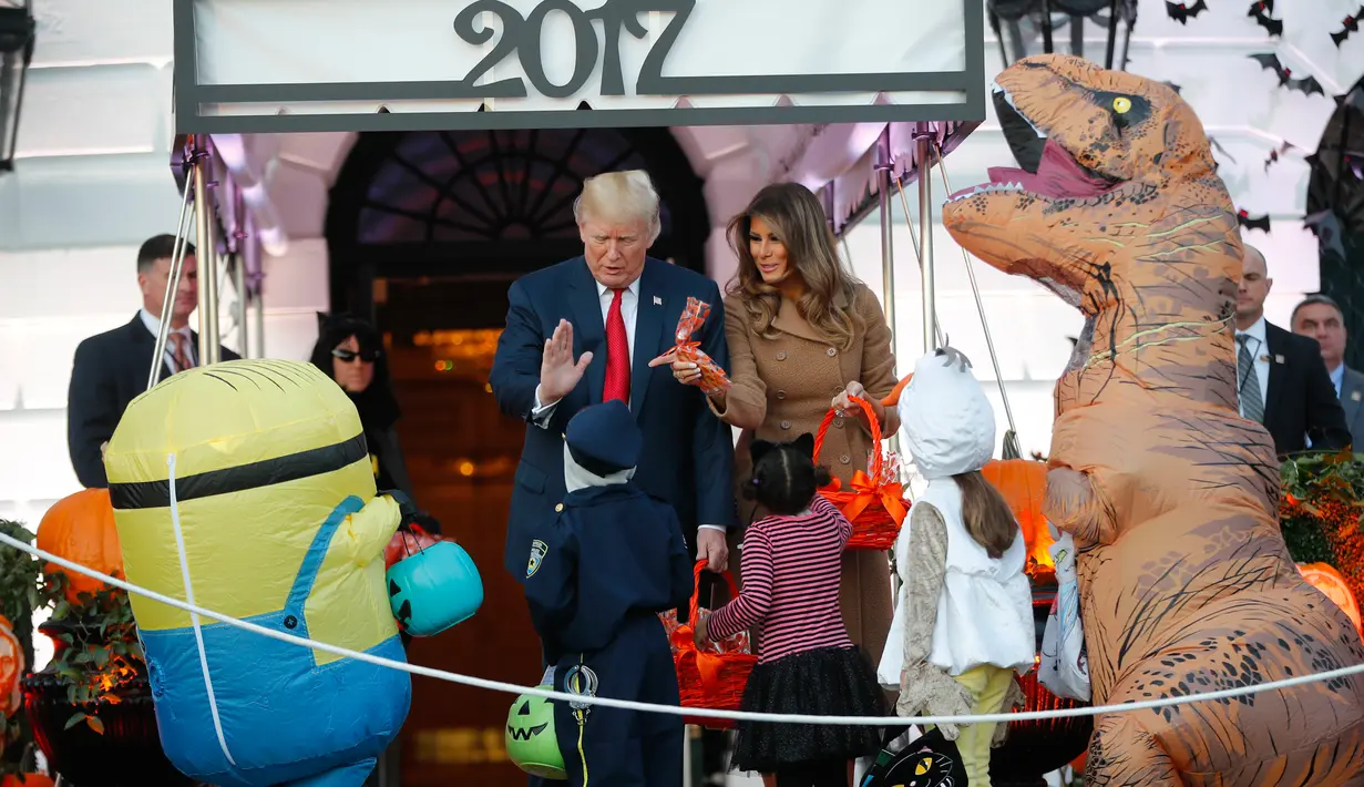 Presiden AS, Donald Trump dan Melania Trump berbincang dengan anak-anak yang melakukan tradisi Trick Or Tread pada perayaan Halloween di Gedung Putih, Senin (30/10). Para siswa dan orang tua dari 20 sekolah hadir di acara ini (AP/Pablo Martinez Monsivais)