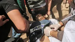 Demonstran membantu wartawan Palestina, Yasser Murtaja, usai ditembak tentara Israel saat meliput protes di perbatasan Gaza-Israel, Jumat (6/4). Sindikat Jurnalis Palestina menyatakan lima jurnalis lain juga ditembak saat meliput protes. (SAID KHATIB/AFP)