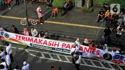 Warga membentangkan spanduk bertuliskan terimakasih Anies Baswedan di kawasan Bundaran HI, Jakarta, Minggu (16/10/2022). Hari terkahir menjabat sebagai Gubernur, Anies berkeliling dengan sepeda menuju Balai Kota. (Liputan6.com/Angga Yuniar)