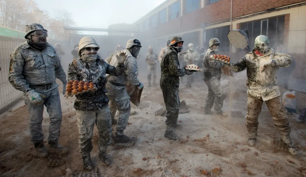 Orang-orang yang bersuka ria mengenakan pakaian militer tiruan saat ikut serta dalam perang makanan "Els Enfarinats" di Kota Ibi, Spanyol, 28 Desember 2022. Para peserta bertarung menggunakan tepung, telur, dan petasan. (JAIME REINA/AFP)