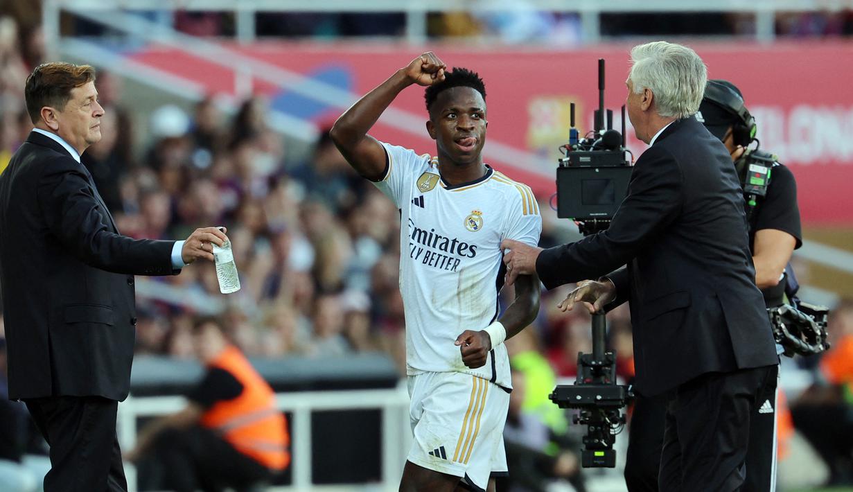 Setelah ditarik keluar lapangan oleh Ancelotti, Vinicius Junior melakukan selebrasi dan coba membuat gesture bak memprovokasi suporter Barcelona. (AFP/Lluis Gene)