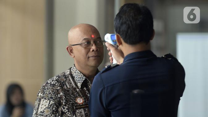Petugas mengecek suhu tamu dan pegawai yang akan masuk ke Loby di Gedung KPK, Jakarta, Kamis, (12/3/2020). KPK menerapkan pengecekan suhu tubuh tersebut untuk mengantisipasi penyebaran virus corona atau covid-19. (merdeka.com/Dwi Narwoko)