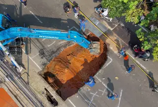 Foto udara menunjukkan aktivitas para pekerja menggunakan alat berat untuk membersihkan puing-puing dari lubang runtuhan yang terbentuk di Jalan Raya Lenteng Agung (arah Depok), Jakarta pada Jumat 29 Mei 2026. (BAY ISMOYO/AFP)