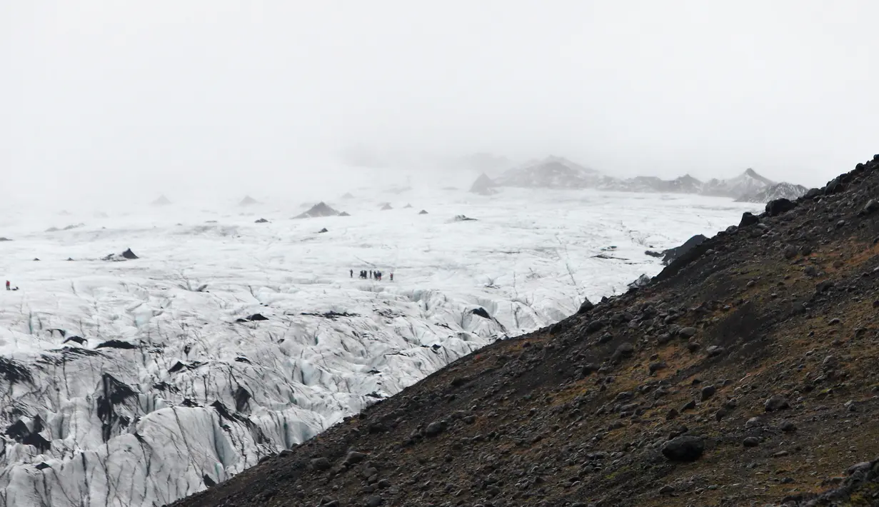 Turis berjalan saat mengunjungi perairan Gletser Solheimajokull, Islandia, Jumat (16/10).  Pemanasan global menyebabkan gletser Solheimajokull mencair hingga 1 km sejak pengukuran tahunan pada 1931. (AFP PHOTO/POOL/Thibault Camus)