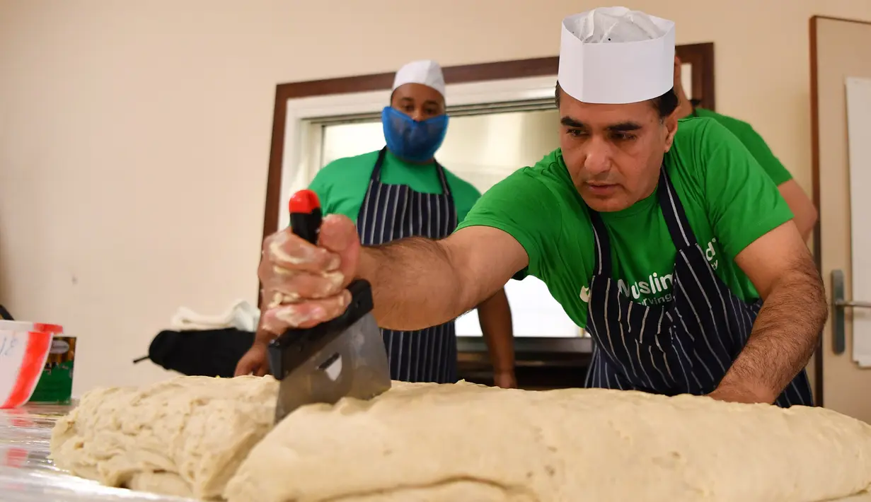 Koki dan relawan Muslim Aid memotong adonan saat membuat makanan ringan berbentuk segitiga, samosa raksasa, di Masjid London Timur, Inggris, Selasa (22/8). Camilan gurih dari India ini berisi 5 kg daging, sayuran dan rempah rempah. (BEN STANSALL/AFP)
