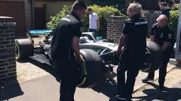 Sejumlah orang mengangkat mobil F1 dari Lewis Hamilton untuk bocah penderita kanker tulang langka Harry Shaw di Redhill, Surrey, Inggris, 13 Mei 2019. Setelah memenangi balapan F1 GP Spanyol, Lewis Hamilton mendedikasikan kemenangan yang diraihnya untuk Harry. (James Shaw/via REUTERS)