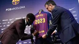 Bek asal Prancis, Samuel Umtiti menandatangani jerseynya disaksikan Presiden Barcelona FC, Josep Maria  pada pengumuman perpanjangan kontraknya di Camp Nou, Senin (4/6). Umtiti memperpanjang kontraknya bersama Barcelona hingga 2022. (LLUIS GENE/AFP)