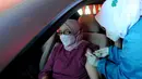 Paramedis menyuntikkan vaksin COVID-19 secara drive thru kepada penumpang mobil di GOR Pajajaran, Kota Bogor, Jawa Barat, Rabu (17/3/2021). Kegiatan ini diselenggarakan oleh Halodoc, Gojek, dan Pemkot Bogor. (merdeka.com/Arie Basuki)