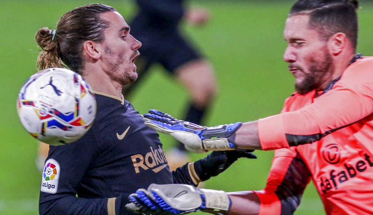 Penyerang Barcelona, Antoine Griezmann, berebut bola dengan kiper Cadiz, Jeremias Ledesma, pada laga Liga Spanyol di Stadion Ramon Carranza, Minggu (6/12/2020). Barcelona takluk dengan skor 1-2. (AP/Alvaro Rivero)