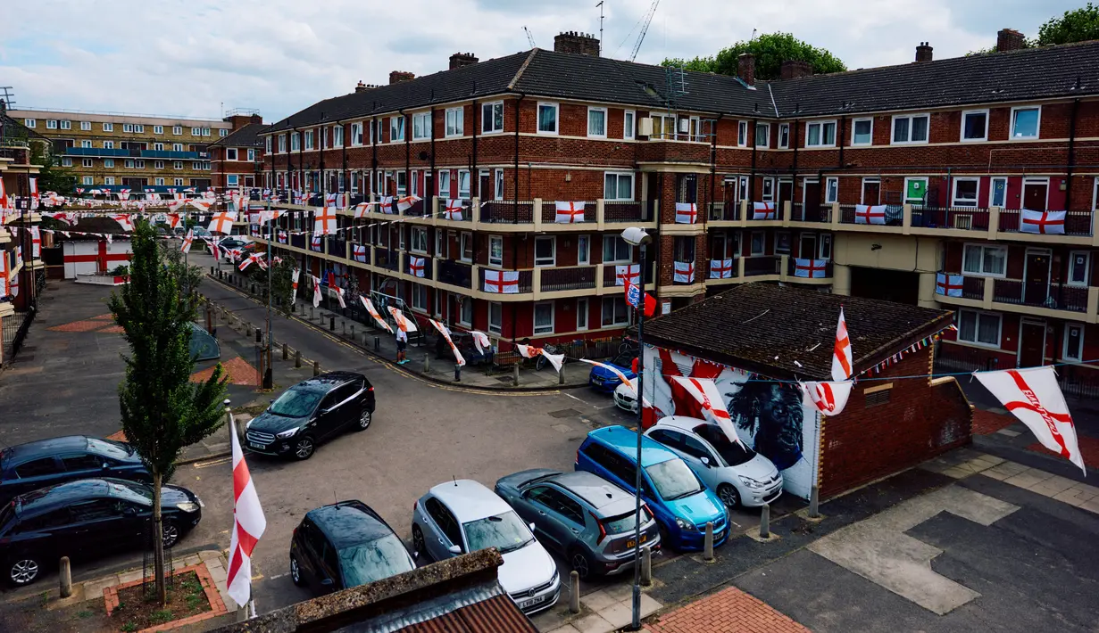 Bendera Inggris itu berjajar rapi di setiap balkon rumah, menggantung di atas lahan parkir, hingga menempel ke tembok gedung. (BENJAMIN CREMEL / AFP)