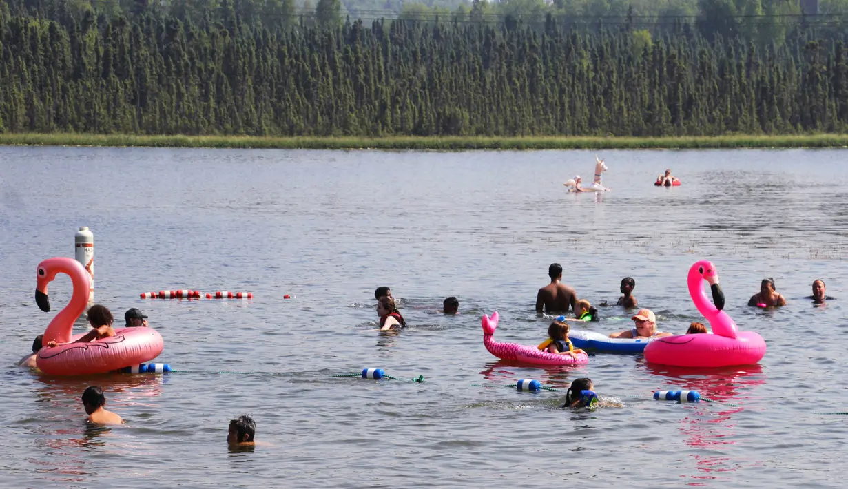 Anak-anak bermain dengan ban karet di Danau Angsa di Anchorage, Alaska (5/7/2019). Suhu pada hari Kamis, 4 Juli, mencapai 90 derajat untuk pertama kalinya di Anchorage dan cuaca panas diperkirakan akan berlanjut hingga minggu depan. (AP Photo/Mark Thiessen)