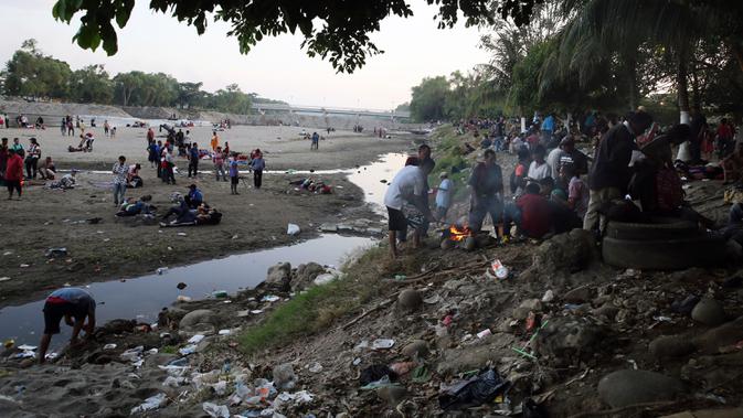 Migran Amerika Tengah beristirahat setelah menyeberangi Sungai Suchiate dengan berjalan kaki dari Guatemala ke Meksiko, Ciudad Hidalgo, Meksiko, Senin (20/1/2020). Lebih dari seribu migran Amerika Tengah berjalan massal untuk menuju Amerika Serikat. (AP Photo/Marco Ugarte)