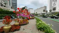 Kendaraan dan pejalan kaki melintasi ornamen dengan nuansa Imlek di kawasan Bundaran HI, Jakarta, Sabtu (29/1/2022). Ornamen yang didominasi warna merah dan emas ini dipasang dalam rangka menyambut perayaan Tahun Baru Imlek 2573, yang jatuh pada 1 Februari mendatang. (Liputan6.com/Herman Zakharia)