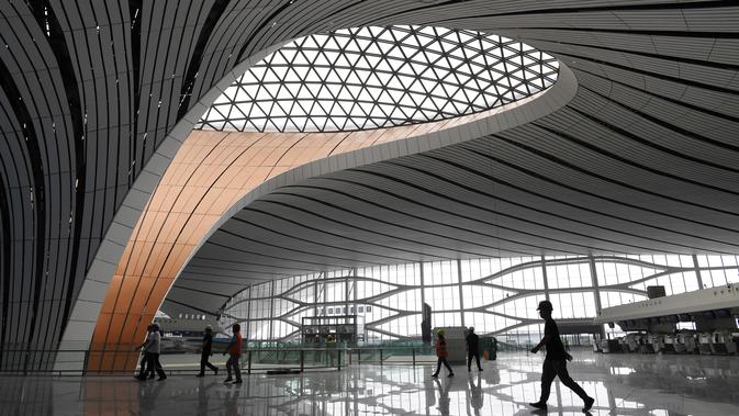 Para pekerja berjalan dalam Terminal Bandara Internasional Daxing Beijing, China, Selasa (9/7/2019). Bandara Internasional Daxing Beijing digadang-gadang akan menjadi yang terbesar di dunia. (GREG BAKER/AFP)