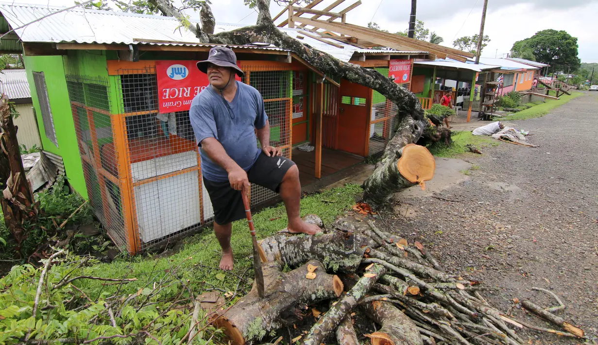 Seorang pria menyingkirkan pohon tumbang akibat badai dahsyat yang menghalangi tokonya di Ibu kota Fiji, Suva, Senin (22/2). Badai tropis Winston memporak-prandakan negara kepulauan Fiji hingga menewaskan sedikinya 10 orang. (REUTERS/Steven Saphore)