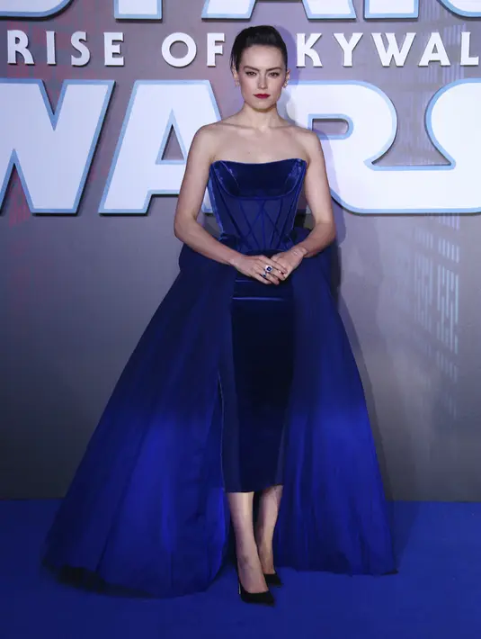 Daisy Ridley berpose saat tiba menghadiri pemutaran perdana film Star Wars: The Rise Of Skywalker" di London (18/12/2019). Aktris 27 tahun ini memilih gaun korset beludru navy yang terstruktur yang menonjolkan tubuh langsingnya dengan rok di pinggangnya. (AP Photo/Joel C Ryan)
