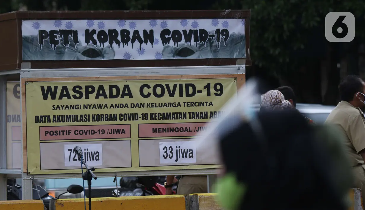 Warga melintasi tanda peringatan bahaya COVID-19 di sekitar Pasar Blok A Tanah Abang, Jakarta, Selasa (1/9/2020). Guna meningkatkan kewaspadaan masyarakat, muspida kecamatan Tanah Abang memajang peti mati dilengkapi data jumlah korban COVID-19 di wilayah tersebut. (Liputan6.comHelmi Fithriansyah)